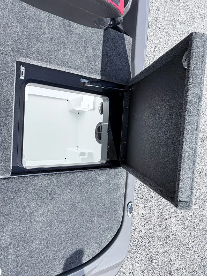 Slide: The Image of Skeeter ZXE21 2026 storage compartment with open lid on gray carpet. - 35