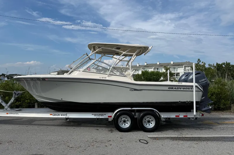 Slide: The Image of 2019 Grady-White Freedom 255 boat on trailer, parked outdoors under a blue sky. - 14