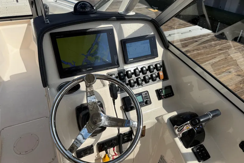 Slide: The Image of 2019 Grady-White Freedom 255 boat dashboard with steering wheel and navigation screens. - 26