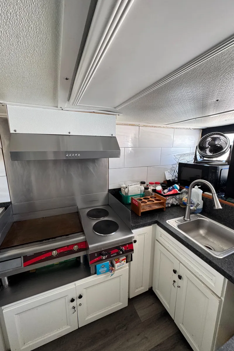Slide: The Image of Compact kitchen in a 1966 Seaway Commercial Sportfish Vessel, featuring stove, sink, and storage cabinets. - 26