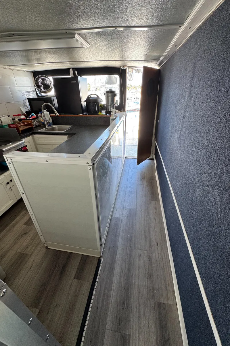 Slide: The Image of Interior of a 1966 Seaway Commercial Sportfish Vessel, featuring a modern kitchenette and wood flooring. - 29