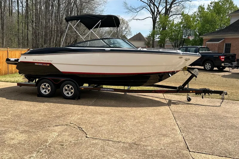 Slide: The Image of 2016 Monterey 238SS Super Sport boat on trailer in driveway, surrounded by trees and houses. - 3