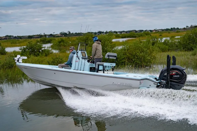 Slide: The Image of 2025 Pathfinder 2300 HPS boat cruising through marshy waters with two passengers. - 2