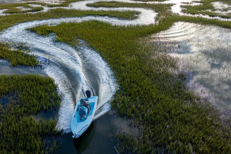 Slide: The Image of Aerial view of 2025 Pathfinder 2300 HPS boat navigating through winding marshland waterways. - 3