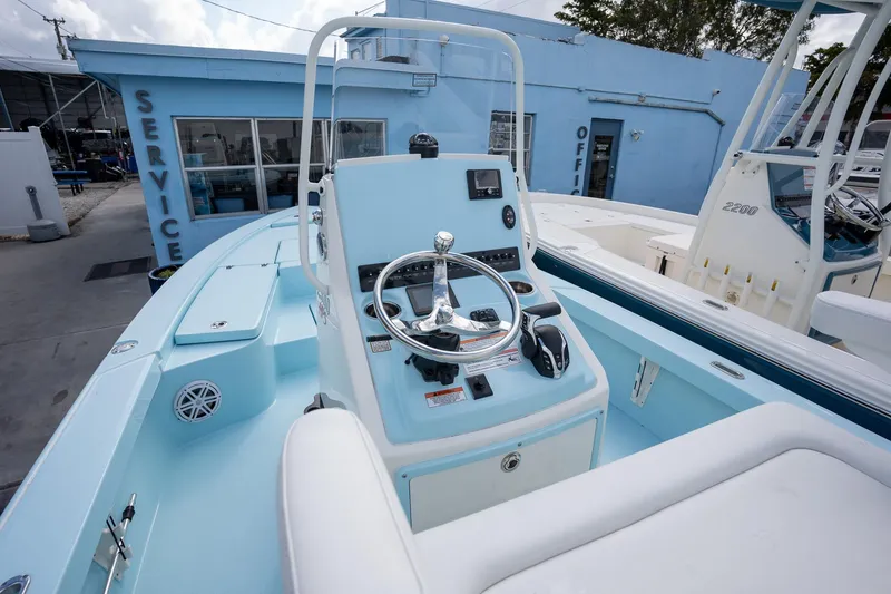 Slide: The Image of 2025 Pathfinder 2300 HPS boat interior with steering console, docked near service building. - 6