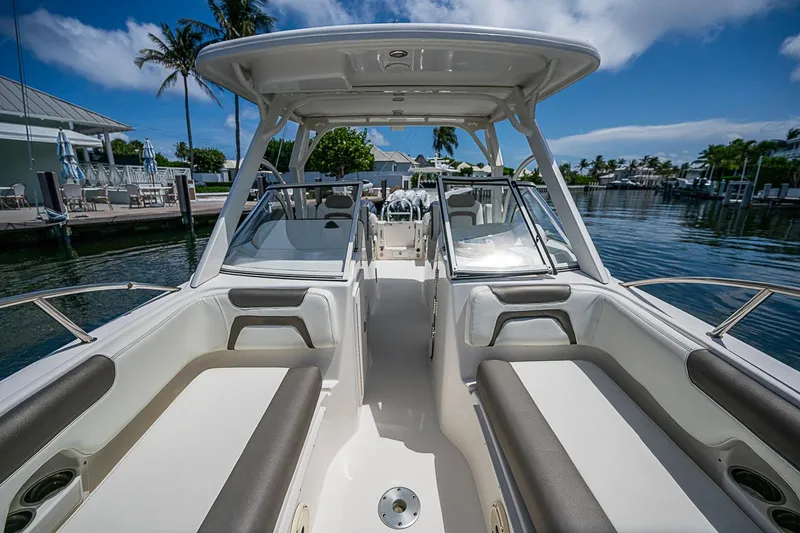 Slide: The Image of 2020 WorldCat 255 DC boat interior with seating, docked by a marina under a clear blue sky. - 13