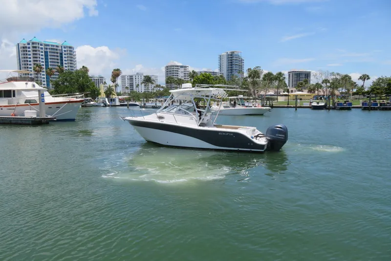 Slide: The Image of 2017 Sea Fox 256 Voyager boat cruising in a marina with cityscape background. - 2
