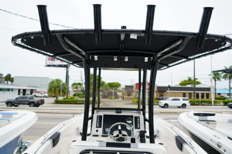 Slide: The Image of 2025 Robalo R222 Center Console boat with T-top and steering wheel, parked outdoors. - 4