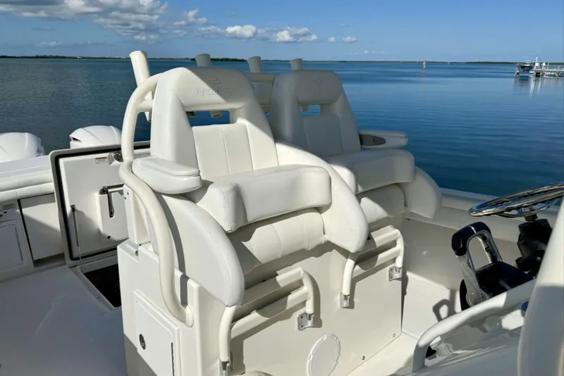 Slide: The Image of 2019 Regulator 31 boat with white seating and steering wheel, on calm water. - 14