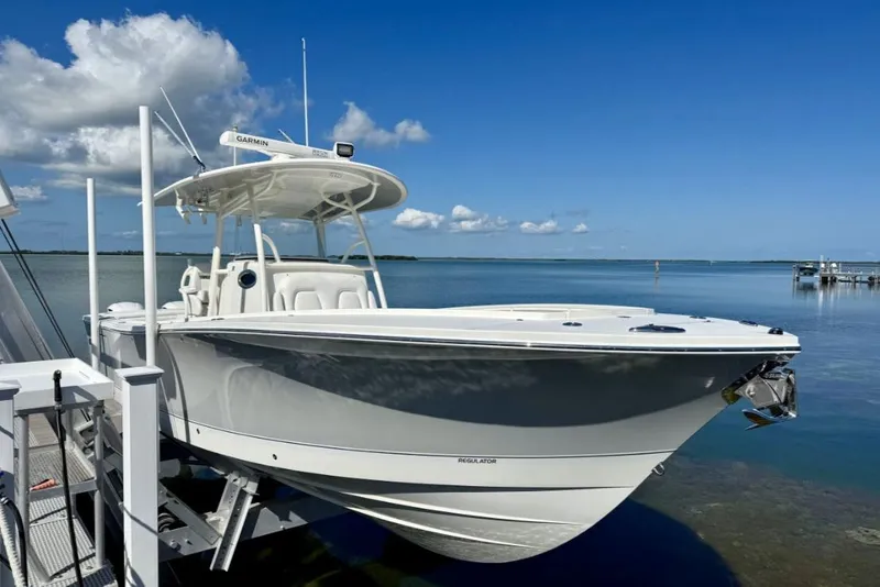 Slide: The Image of 2019 Regulator 31 boat docked by the water under a clear blue sky. - 2