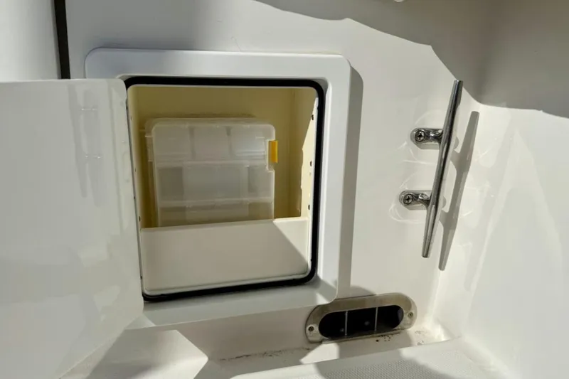 Slide: The Image of Storage compartment on a 2019 Regulator 31 boat, featuring a tackle box and stainless steel hardware. - 23