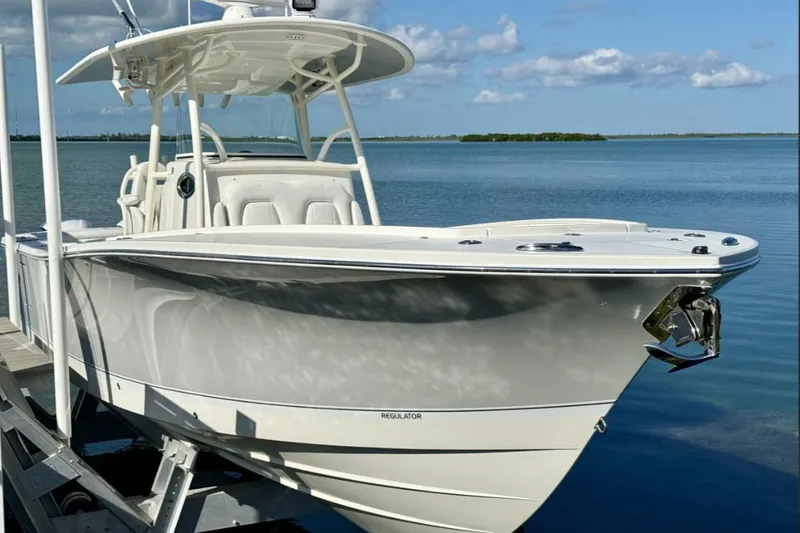 Slide: The Image of 2019 Regulator 31 boat docked by serene blue waters under a clear sky. - 49