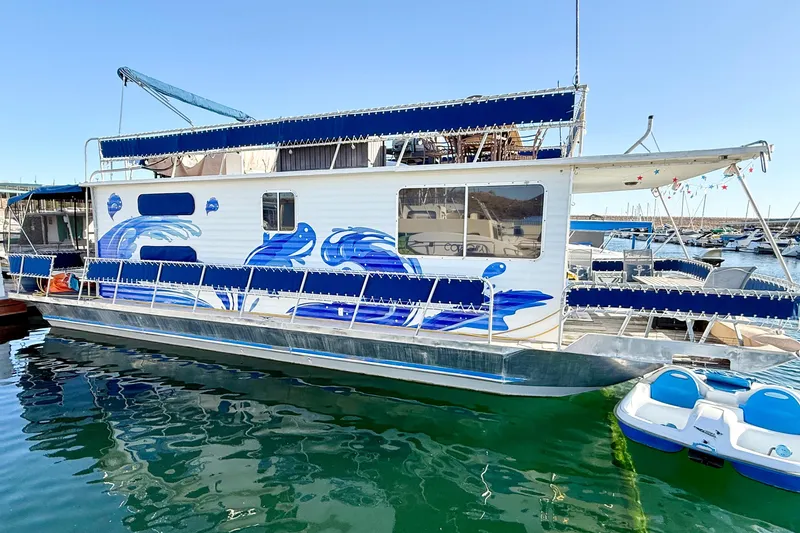 The Image of 1986 Hilburn 4014 Executive houseboat with blue wave design docked in marina. - 1