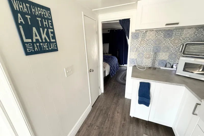 Slide: The Image of Cozy interior with lake-themed decor, featuring a kitchenette and bedroom in a Hilburn 4014 Executive. - 11