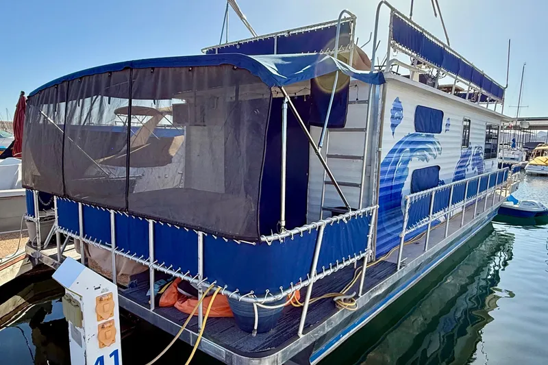 Slide: The Image of 1986 Hilburn 4014 Executive houseboat with blue wave design docked at marina. - 24