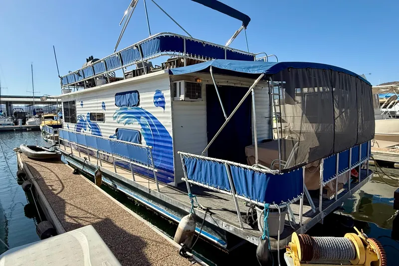 Slide: The Image of 1986 Hilburn 4014 Executive houseboat docked, featuring blue wave design and covered deck area. - 25