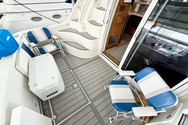 Slide: The Image of 2007 Carver 36 Sedan yacht deck with striped chairs and cooler, leading to cabin interior. - 14