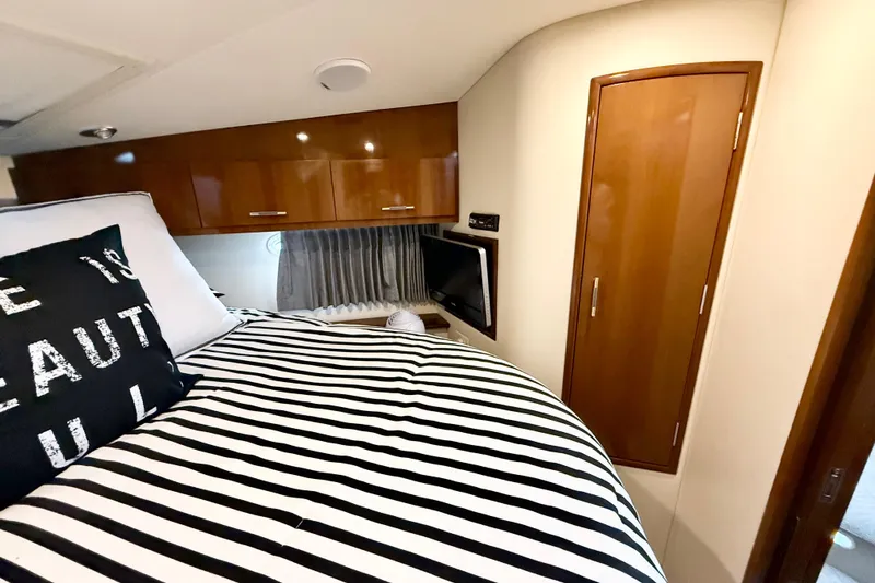 Slide: The Image of Interior of 2007 Carver 36 Sedan with striped bedding and wooden cabinetry. - 29