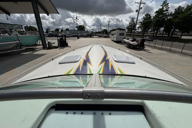 Slide: The Image of 2002 Formula 292 FASTech boat with vibrant lightning graphics, parked at a marina under cloudy skies. - 21