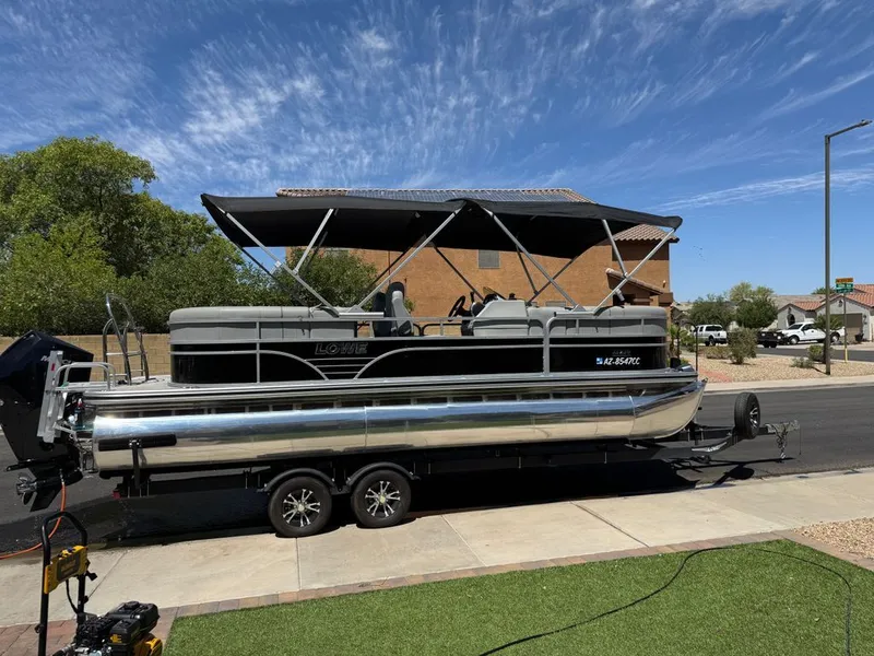 Slide: The Image of 2021 Lowe SS pontoon boat on trailer under blue sky. - 1