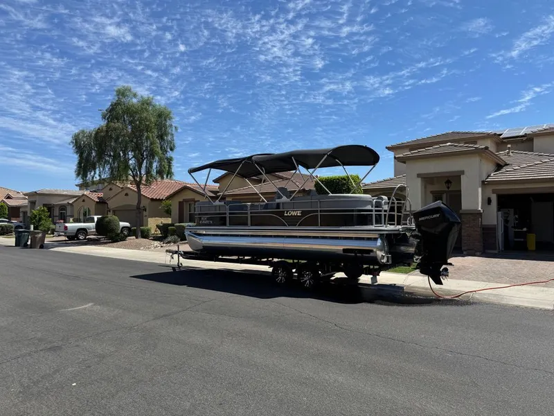 Slide: The Image of 2021 Lowe pontoon boat parked on residential street, blue sky. - 10