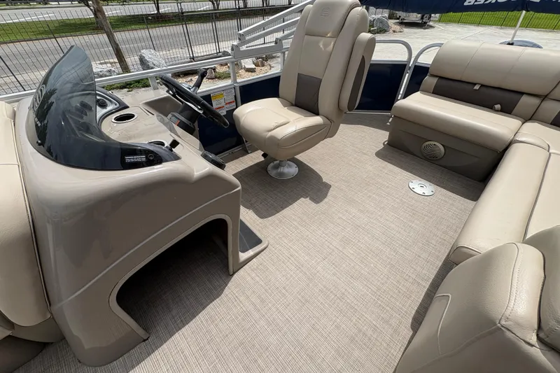 Slide: The Image of 2021 Sun Tracker Party Barge 20 DLX interior with beige seating and steering console. - 15