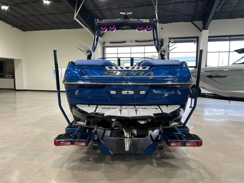 Slide: The Image of Rear view of a blue 2021 Supra SL 400 boat in showroom. - 4