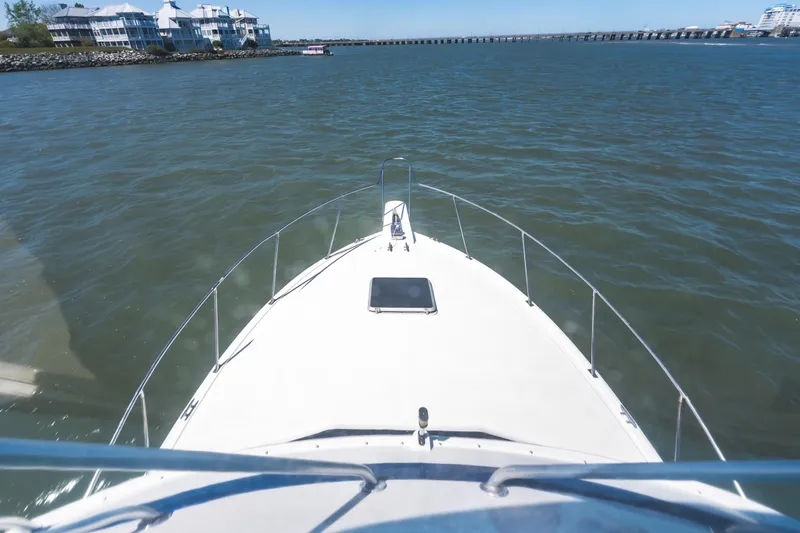 Slide: The Image of 1986 Bertram 35 Flybridge Sportfish cruising on calm waters near coastal buildings. - 13
