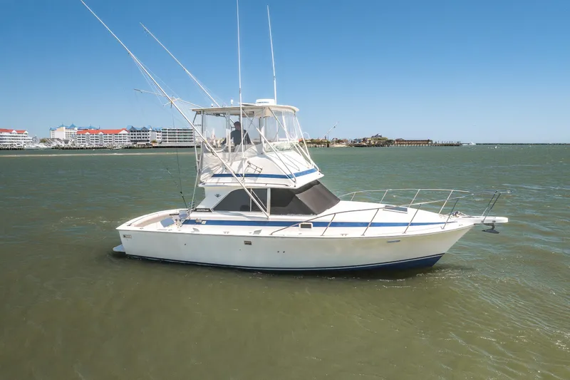 Slide: The Image of 1986 Bertram 35 Flybridge Sportfish boat on calm waters, clear sky background. - 2