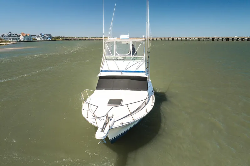 Slide: The Image of 1986 Bertram 35 Flybridge Sportfish boat on calm waters near a coastal area. - 5