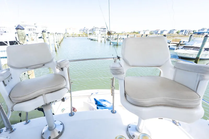 Slide: The Image of Two white captain chairs on a 1986 Bertram 35 Flybridge Sportfish boat, overlooking a marina. - 9