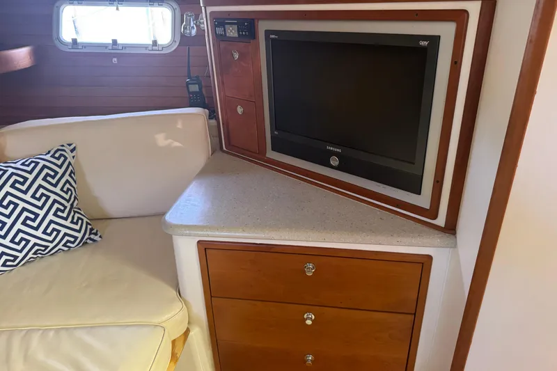 Slide: The Image of Interior of 2006 MJM 34z Downeast boat with TV, wooden cabinets, and cushioned seating. - 13