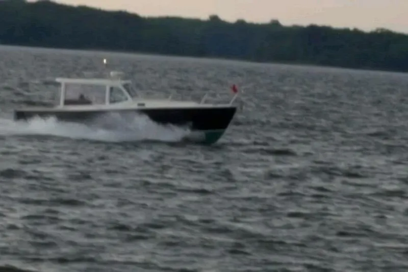 Slide: The Image of 2006 MJM 34z Downeast boat cruising on a lake with forested shoreline. - 16