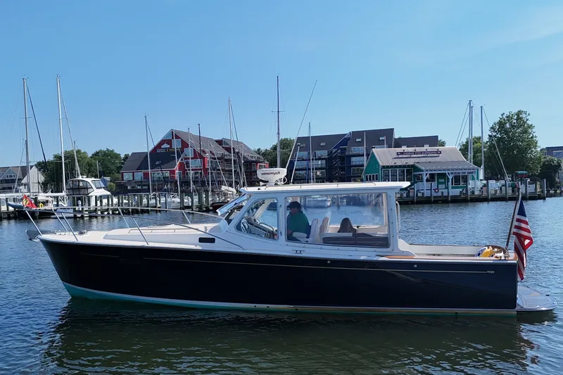 Slide: The Image of A 2006 MJM 34z Downeast boat on the water, with docks and buildings in the background. - 4