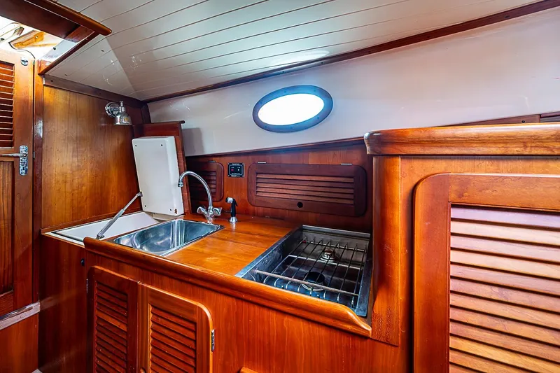 Slide: The Image of 1996 Hinckley Picnic Boat 36 Classic interior galley with wooden cabinetry and stainless steel sink. - 13