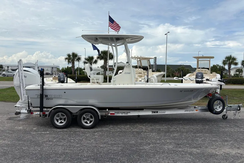 Slide: The Image of 2025 Pathfinder 2200 TRS boat on trailer with American flag, parked outdoors. - 4