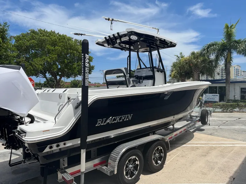 Slide: The Image of 2019 Blackfin 242 CC boat on trailer, parked outdoors under a clear blue sky. - 2