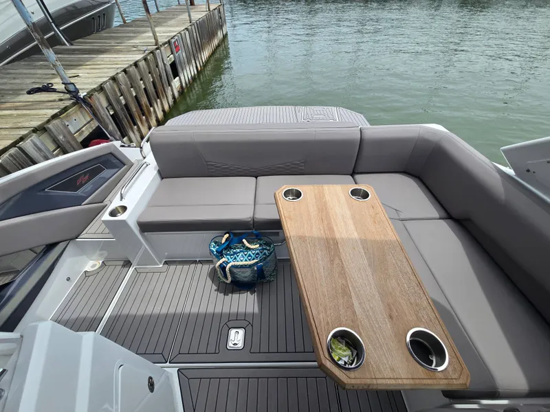 Slide: The Image of Interior of a 2021 Cruisers Yachts 338 with wooden table and gray seating. - 18