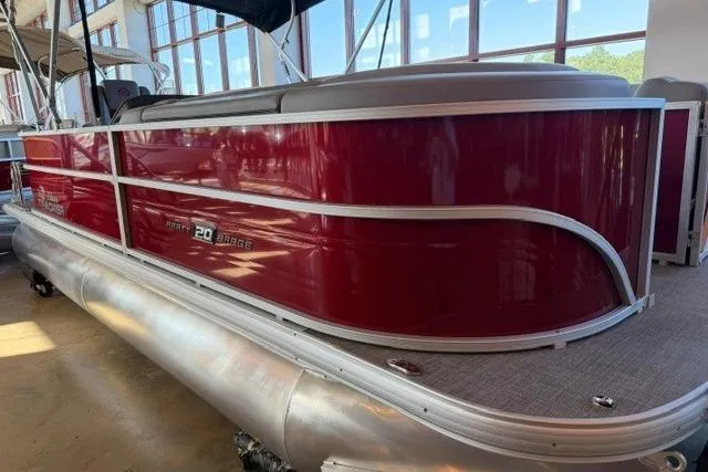 Slide: The Image of 2026 Sun Tracker Party Barge 20 DLX pontoon boat with red exterior in showroom. - 1