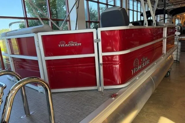Slide: The Image of 2026 Sun Tracker Party Barge 20 DLX, red exterior, docked indoors. - 2