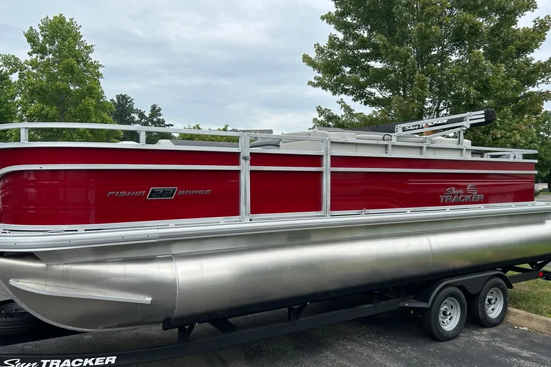 Slide: The Image of 2026 Sun Tracker Fishin' Barge 22 DLX pontoon boat on trailer, red exterior. - 1
