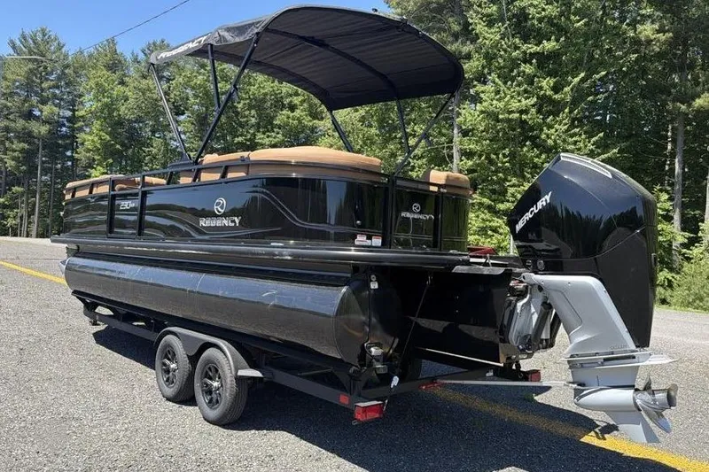 Slide: The Image of 2026 Regency 230 DL pontoon boat with Mercury outboard motor on trailer, parked outdoors. - 2