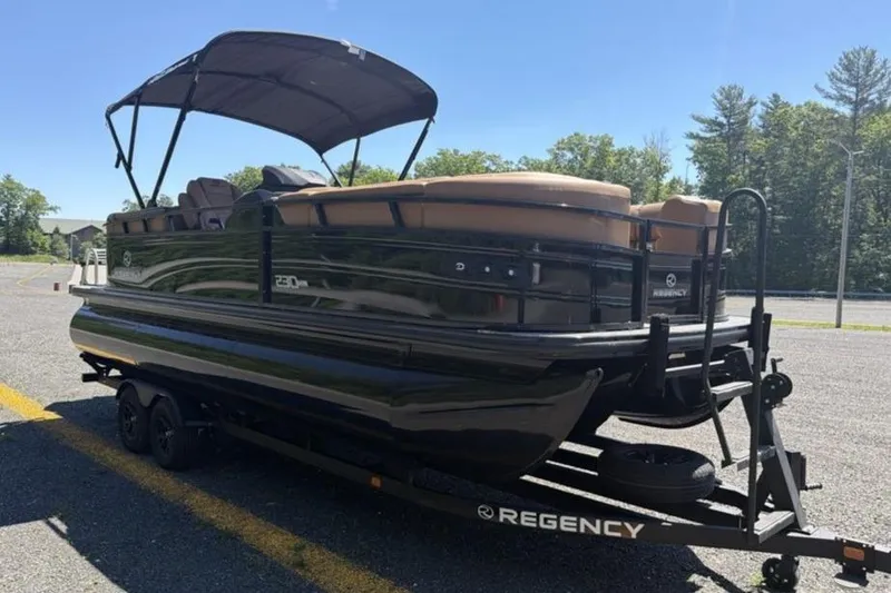 Slide: The Image of 2026 Regency 230 DL pontoon boat on trailer, parked outdoors. - 3