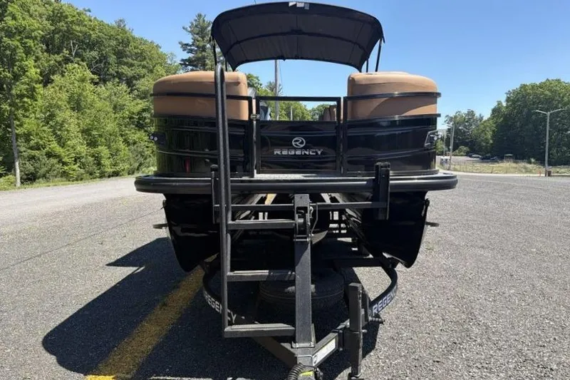 Slide: The Image of 2026 Regency 230 DL pontoon boat on trailer, parked on a sunny road. - 6