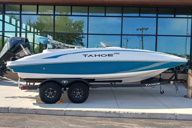 The Image of 2026 Tahoe 2150 boat on trailer, parked outside a glass building. - 0