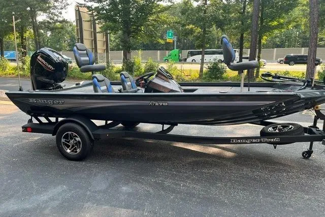 Slide: The Image of 2026 Ranger RT178 fishing boat on trailer, parked outdoors with trees in the background. - 2
