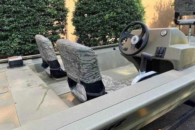 Slide: The Image of 2026 Tracker Grizzly 1754 SC boat interior with camo seats and steering console. - 3