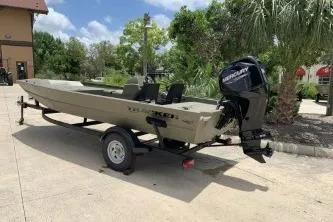 Slide: The Image of 2026 Tracker Grizzly 1754 SC boat on trailer, outdoors with trees and building in background. - 5