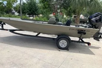Slide: The Image of 2026 Tracker Grizzly 1754 SC boat on trailer, outdoors with trees in background. - 2