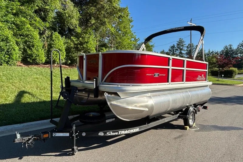 Slide: The Image of 2026 Sun Tracker Party Barge 16 DLX pontoon boat on trailer, parked outdoors. - 2